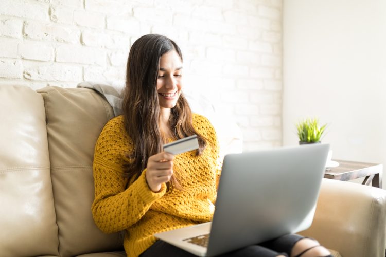 Carefree woman purchasing online using wireless computer on sofa at home